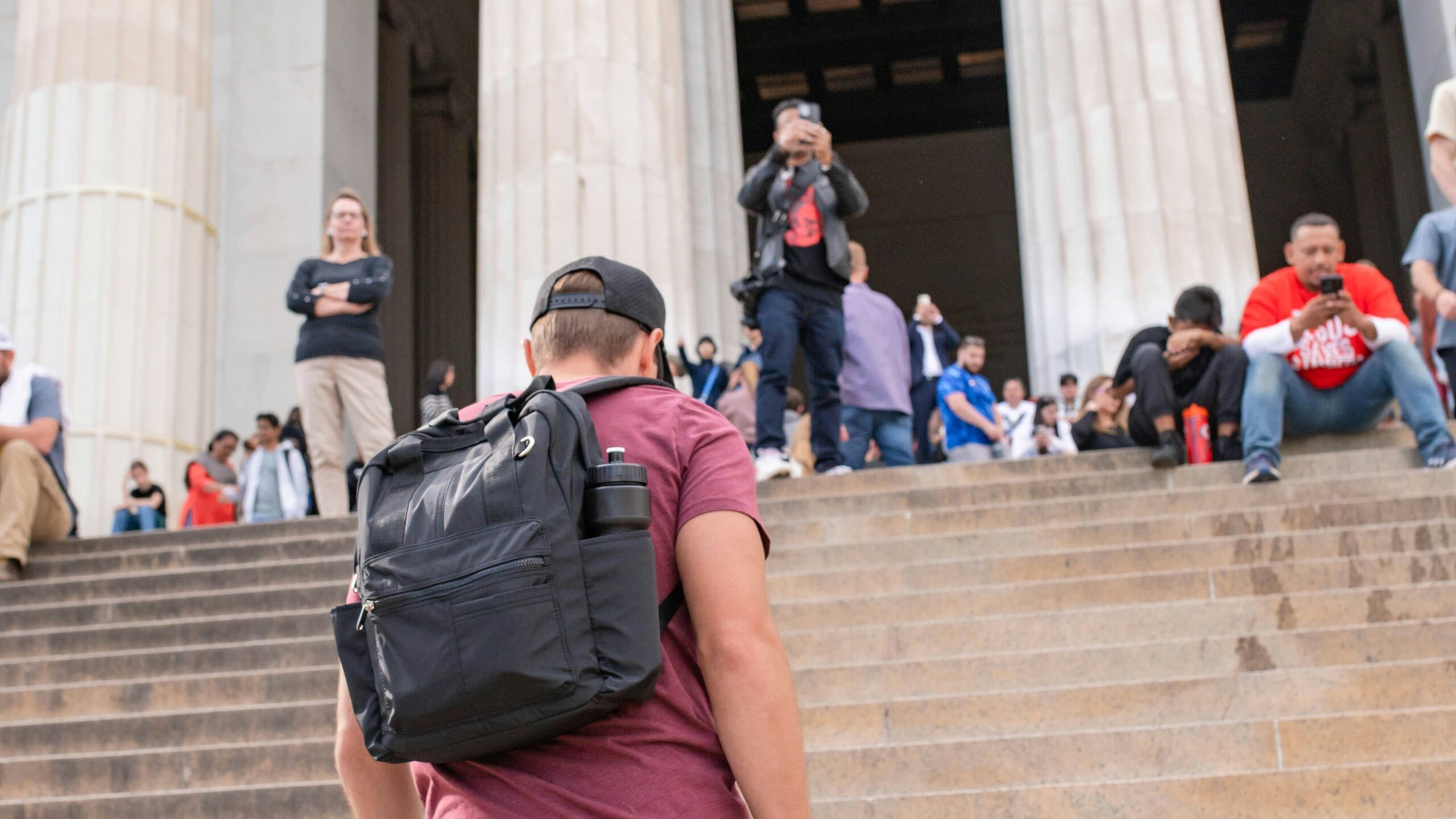 A man walks up steps towards a monument.
