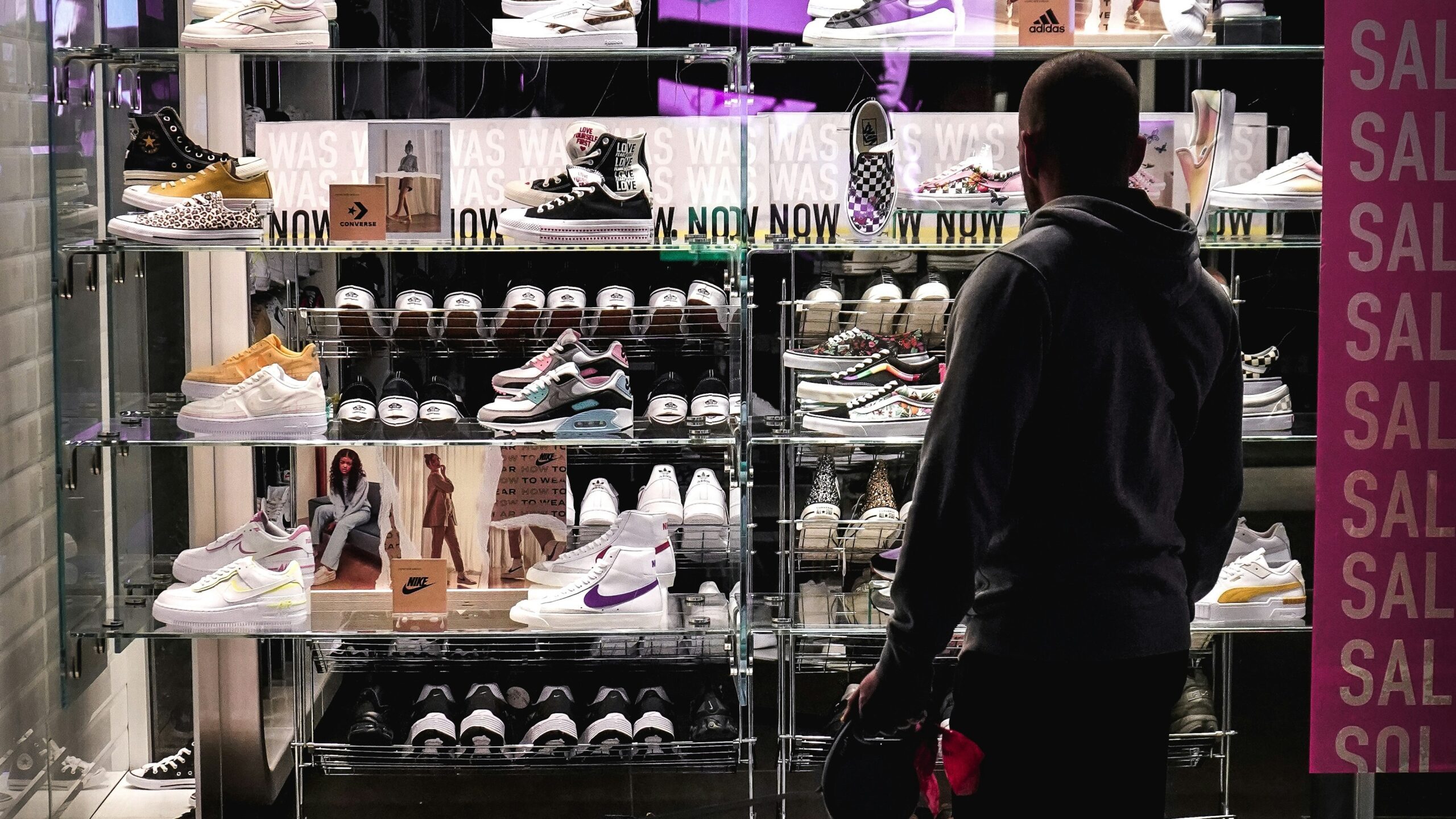 man in black long sleeve shirt standing near shoe rack