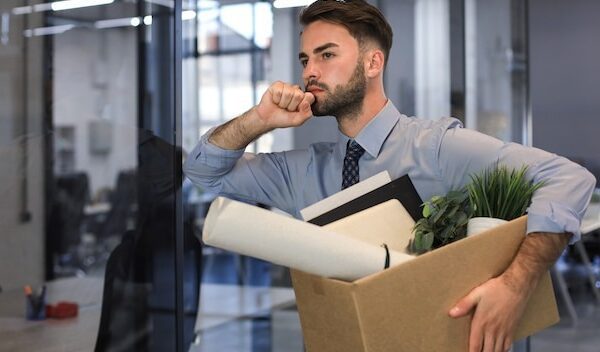 Sad dismissed worker is taking his office supplies with him from office.