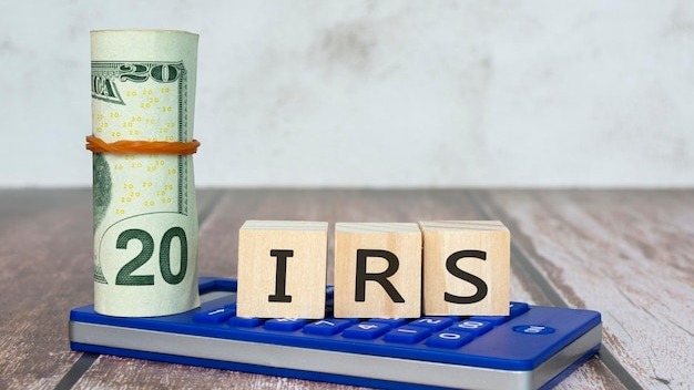 IRS Text IRS Internal Revenue Service On Wooden blocks with dollar bill and calculator