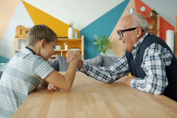 Grandfather and grandson arm wrestling at table