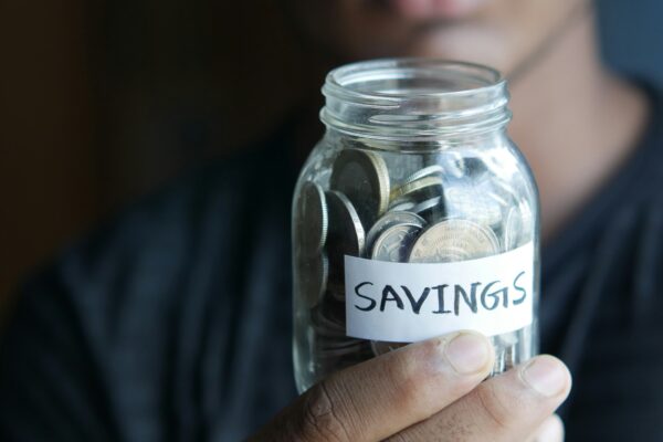 a man holding a jar with a savings label on it