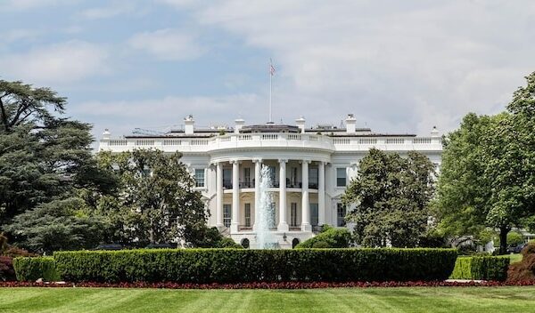 Grassy field with white house in background