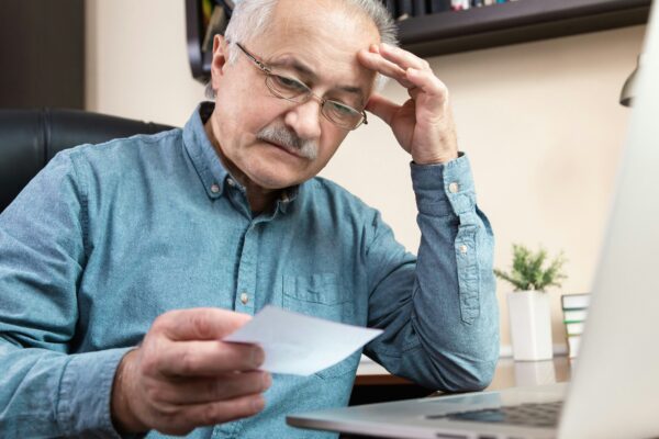 a man holding a pen and looking at a laptop