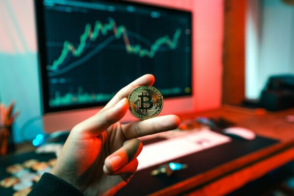 a person holding a coin in front of a computer