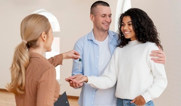 Female realtor handing smiley couple the keys for their new home