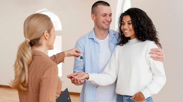 Female realtor handing smiley couple the keys for their new home