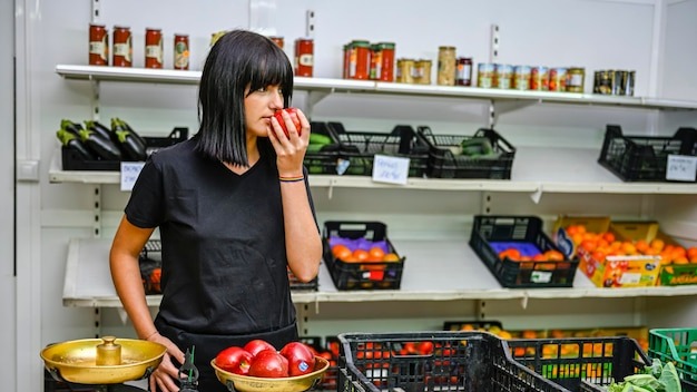 Portrait of shopkeeper in the greengrocer smelling an apple