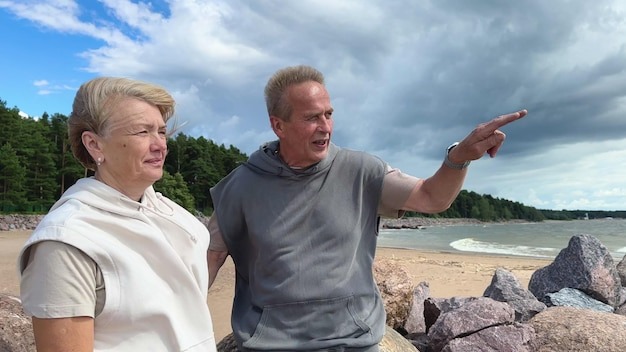 Portrait of happy elderly senior couple in love walking on a beach at summer smile laugh have fun
