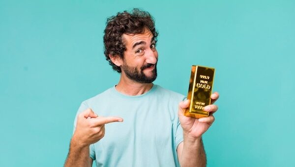 Young adult hispanic crazy man holding a gold ingot