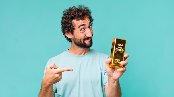 Young adult hispanic crazy man holding a gold ingot