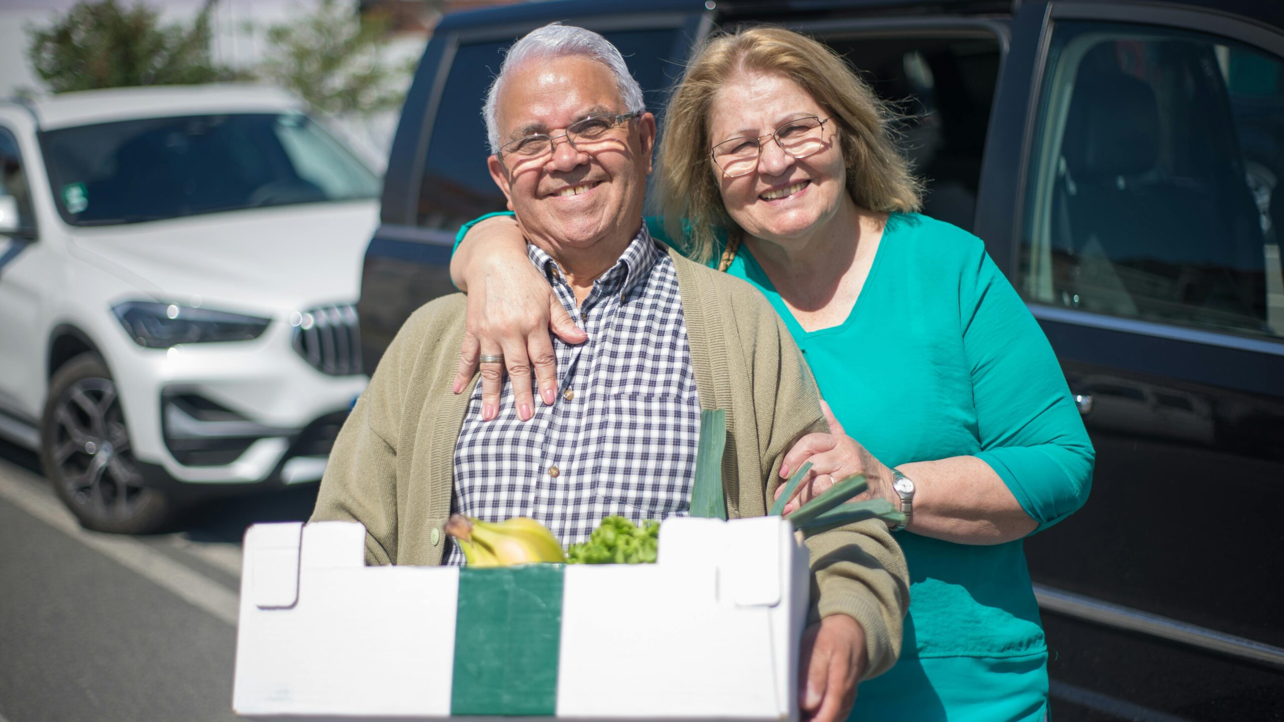 Elderly couple happily shopping with a grocery box outdoors in Portugal.