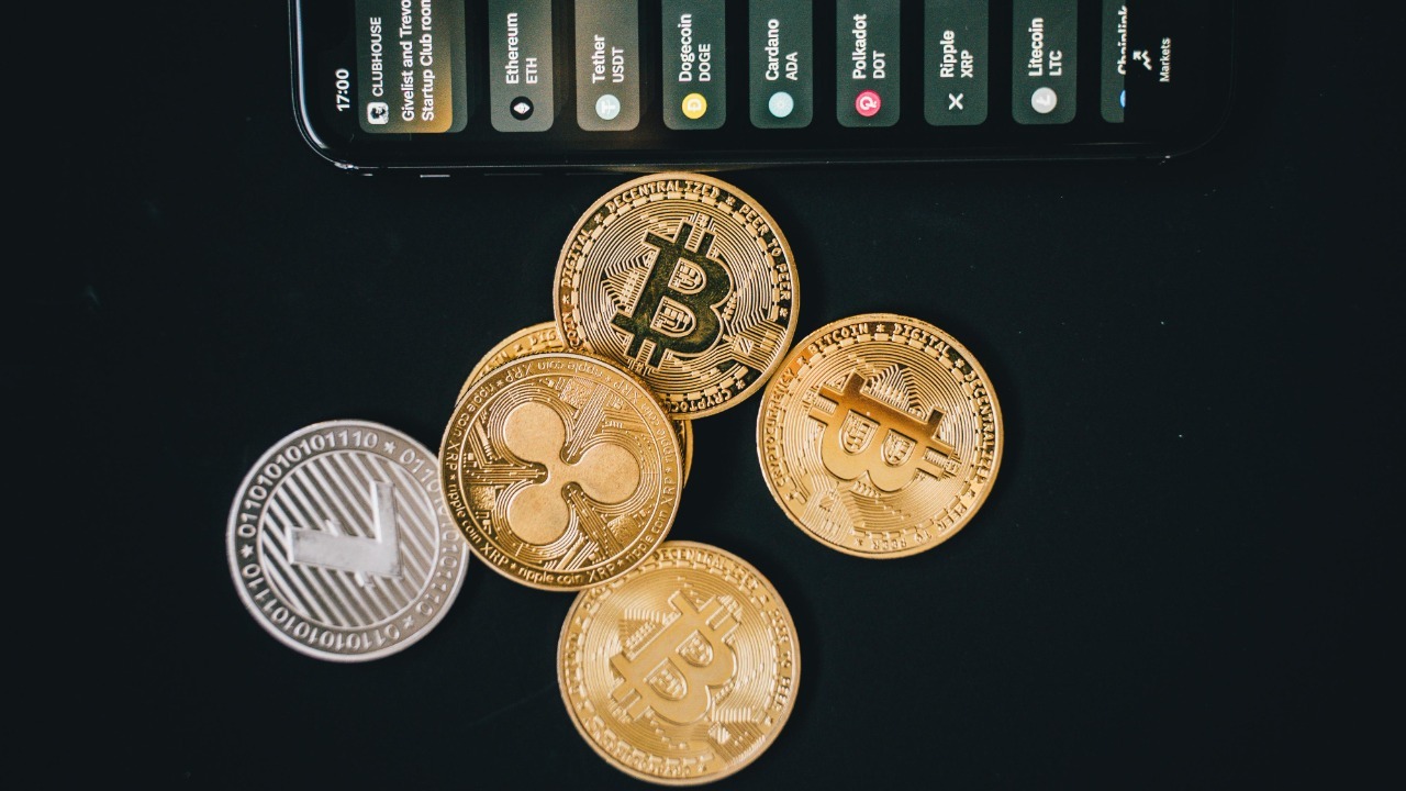 Close-up of various cryptocurrencies and a smartphone showing market trends.