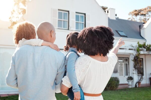 Real estate love and family in the yard of their new house bonding and spending quality time together Mortgage luxury property and back of young mom dad and children standing by their modern home