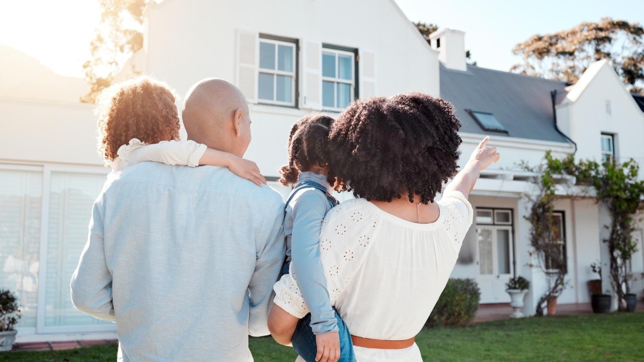 Real estate love and family in the yard of their new house bonding and spending quality time together Mortgage luxury property and back of young mom dad and children standing by their modern home