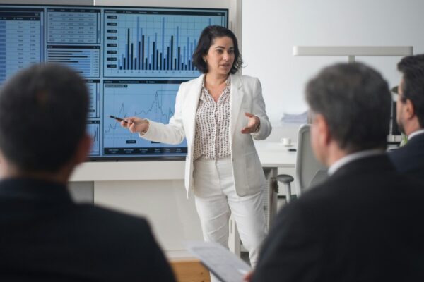 Professional woman presenting stock market data in a modern office setting.
