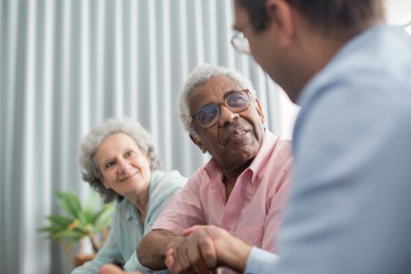 Elderly couple discussing with a consultant indoors, expressing interest and connection.