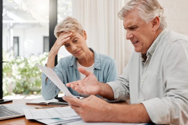 Sad retirement couple finance debt and anxiety in financial planning mortgage home loan and paper bills Stress woman angry man and senior people pension problem admin crisis and budget mistake