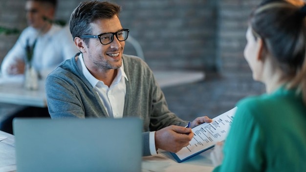 Happy businessman talking to his colleague while going through financial reports in the office