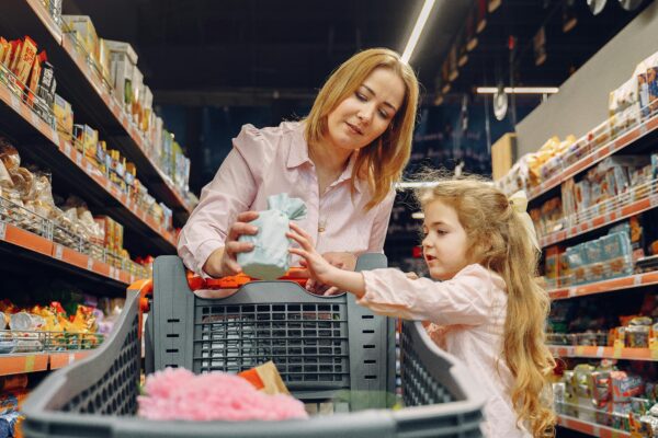 A mother and daughter shopping together in a supermarket aisle, enjoying quality time.