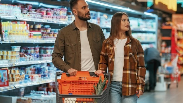 Choosing the products Young couple are in supermarket together