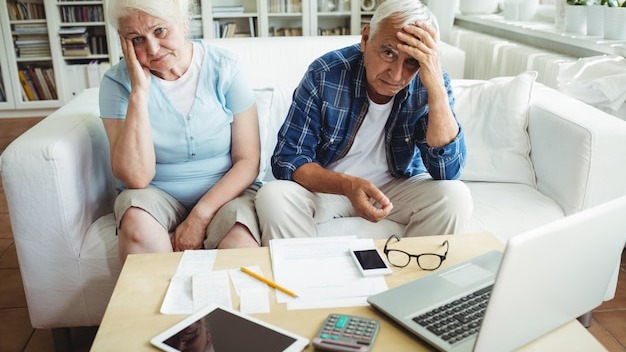 Worried senior couple sitting on sofa