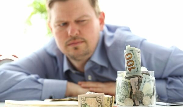 Man looking at jar full of money thinking about his debts