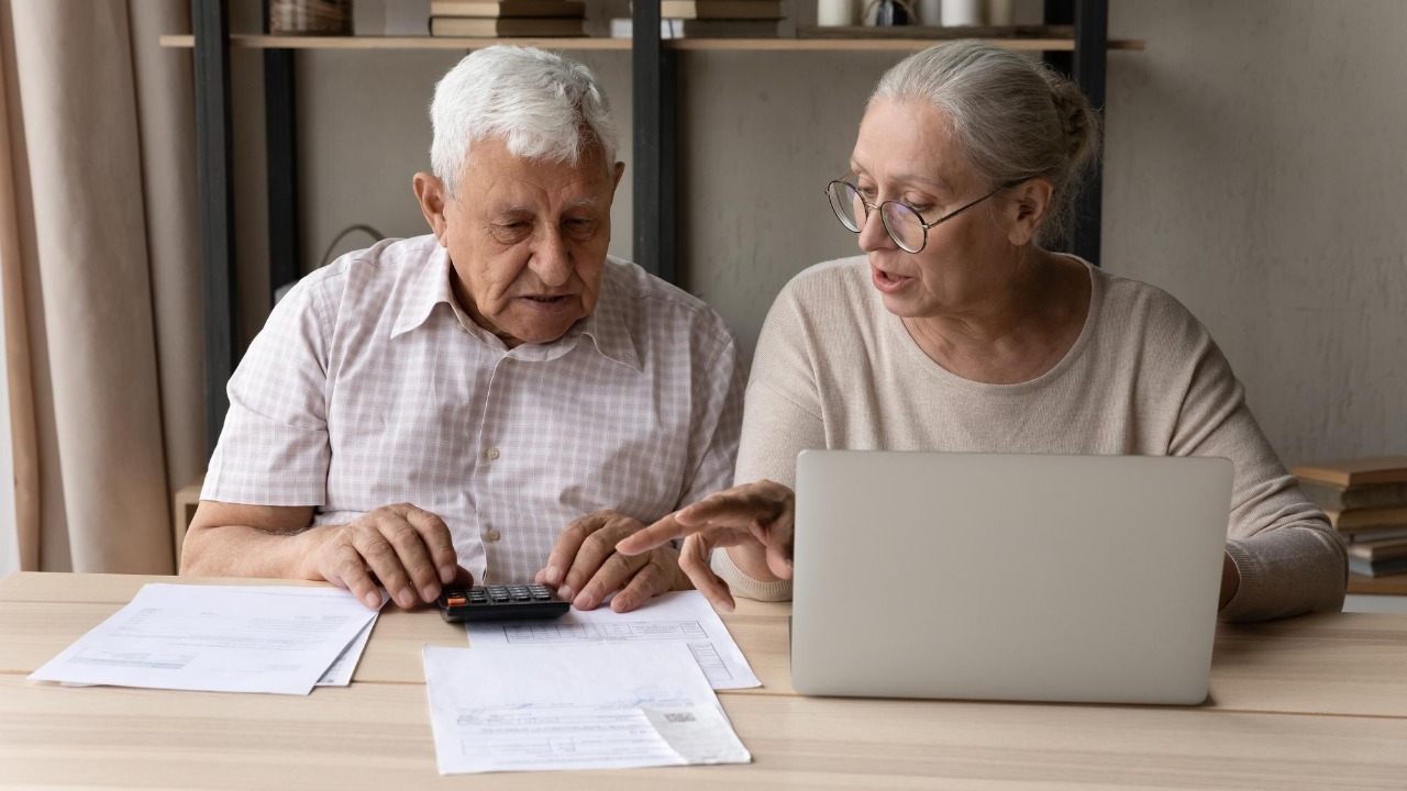 Concentrated middle aged mature family couple calculating domestic expenditures or taxes managing monthly budget paying taxes or bills in computer ebanking application planning investment