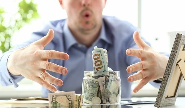 Male hands grabbing big fat jar full of US currency as greed gesture