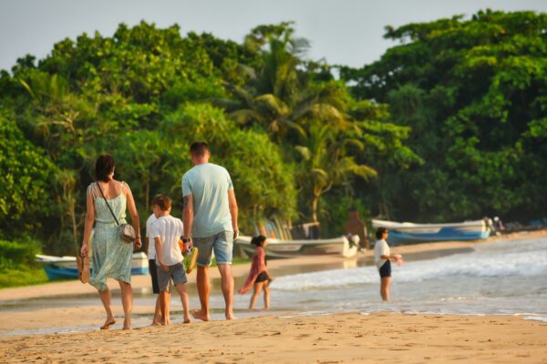 A family walks on a beach near the water.