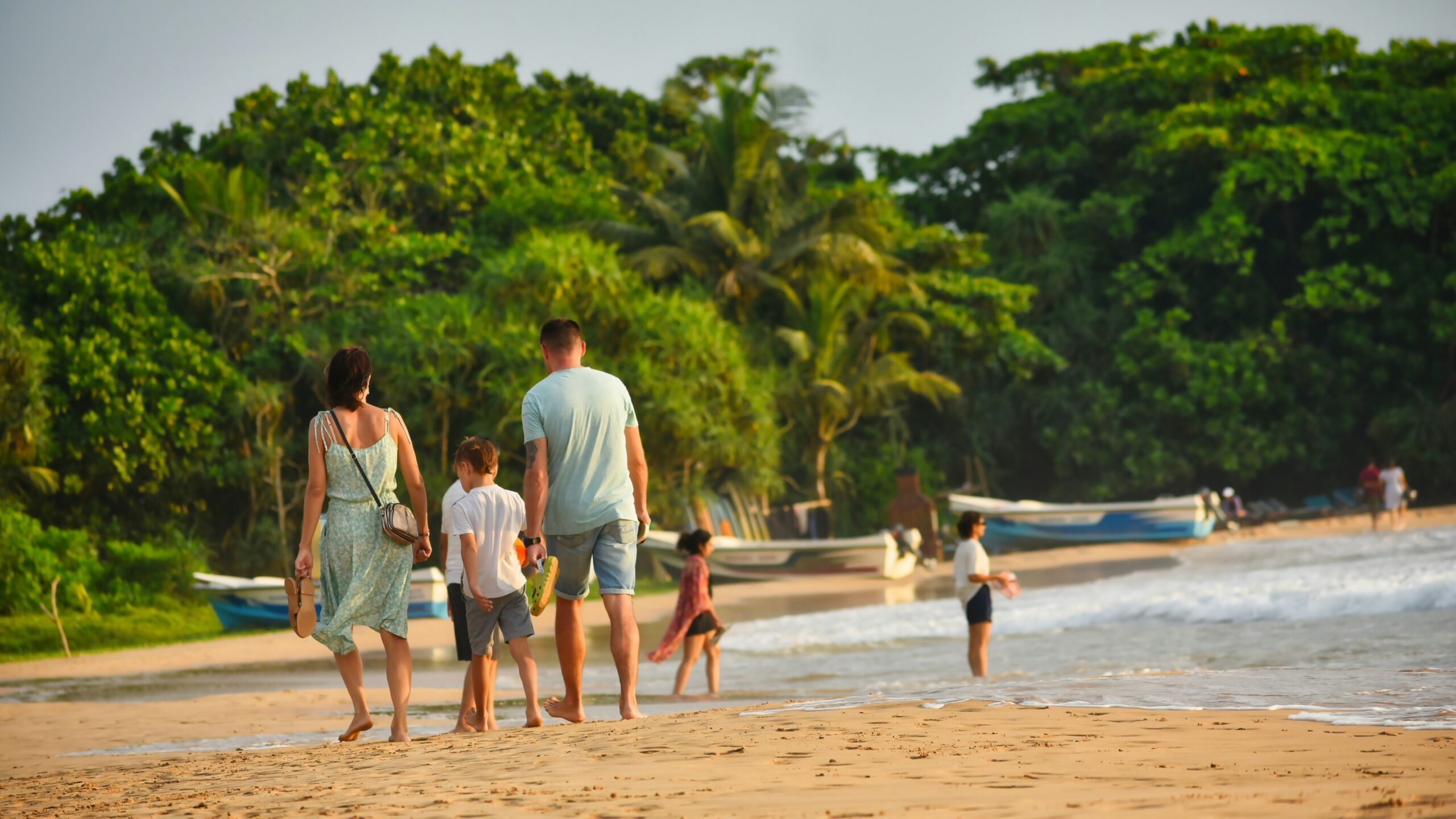 A family walks on a beach near the water.