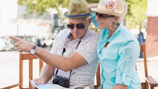 Happy tourist couple looking at map in the city