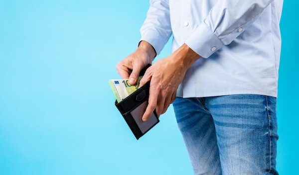 View of the man taking out cash from his wallet on a blue background