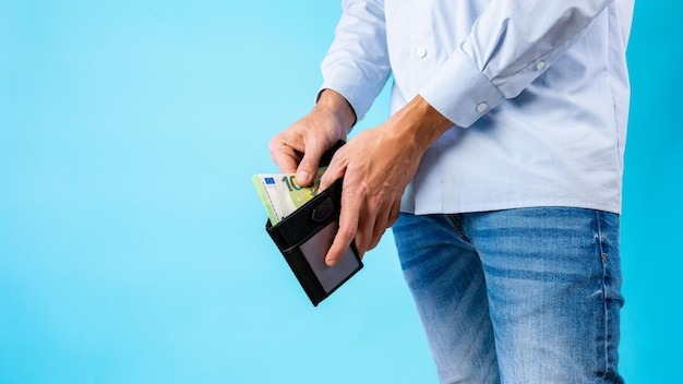 View of the man taking out cash from his wallet on a blue background