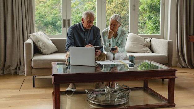 Active senior couple calculating bills in living room