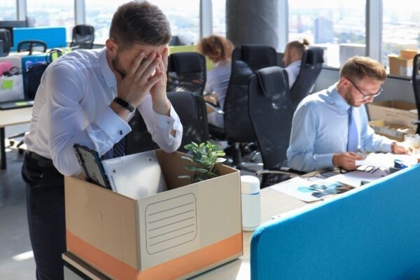 Sad dismissed worker are taking his office supplies with him from office.