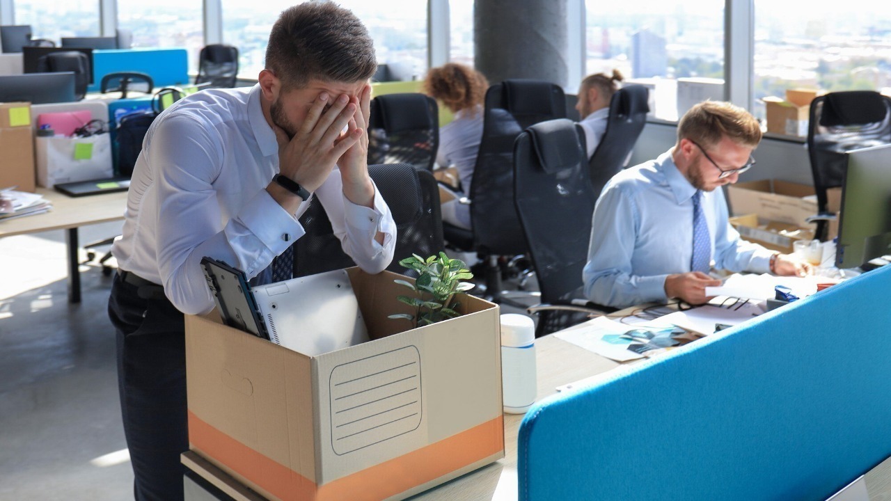 Sad dismissed worker are taking his office supplies with him from office.