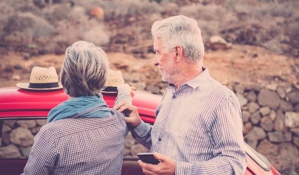 Senior couple standing by car
