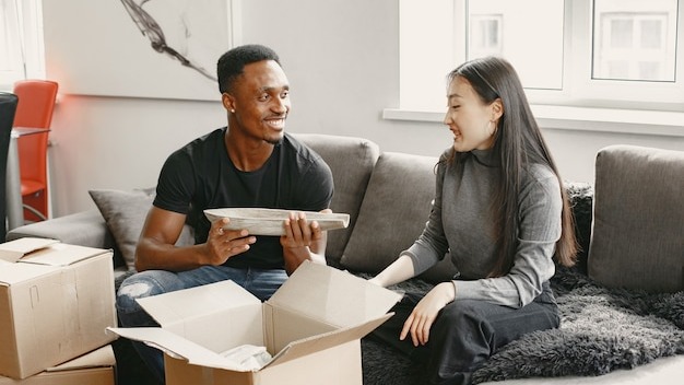 Portrait of young couple with cardboard boxes at new home, moving house concept.