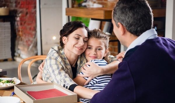 Beautiful mother and daughter hugging warmly at a dinner table