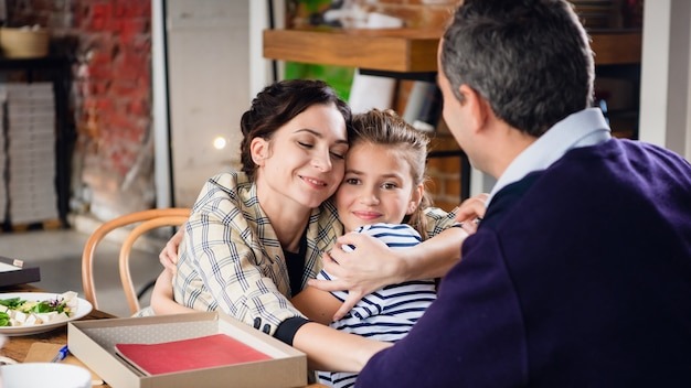 Beautiful mother and daughter hugging warmly at a dinner table