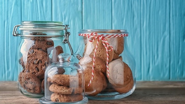 Glass jars with delicious oatmeal cookies on wooden table