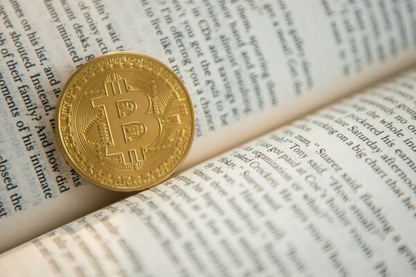gold-colored Bitcoin on book