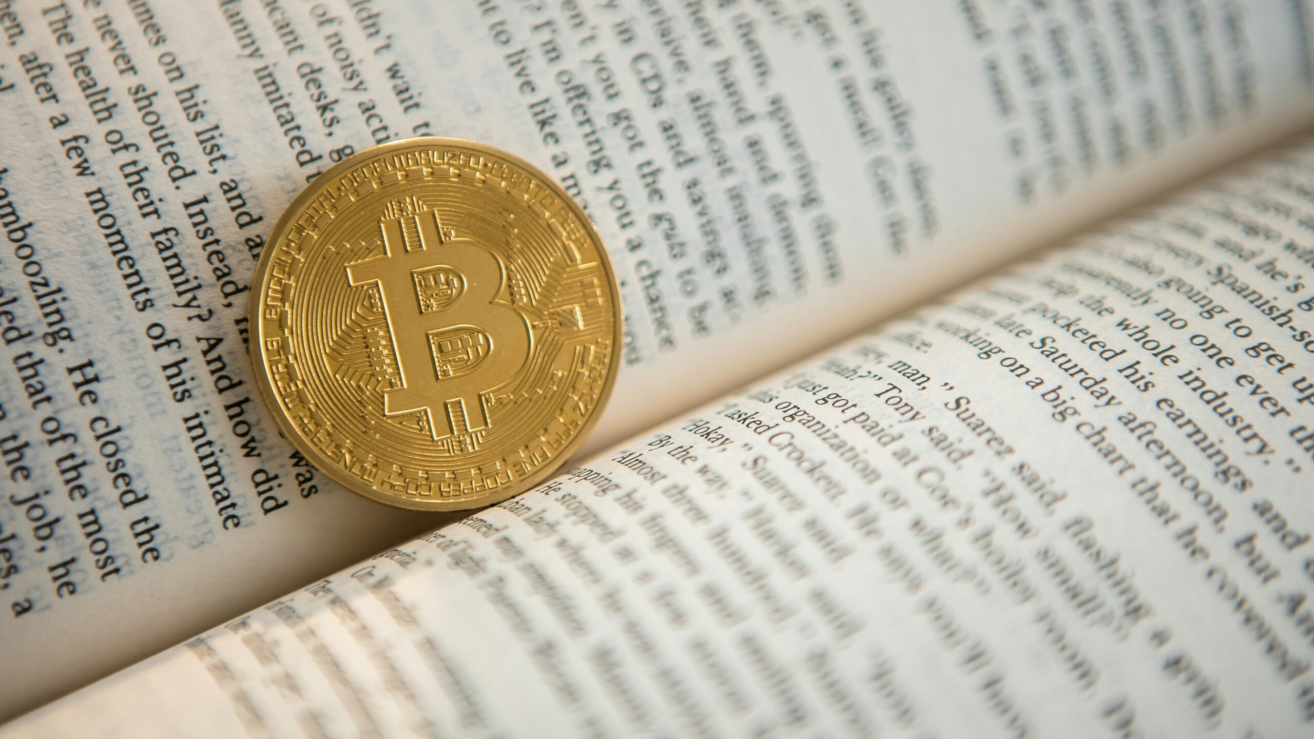 gold-colored Bitcoin on book