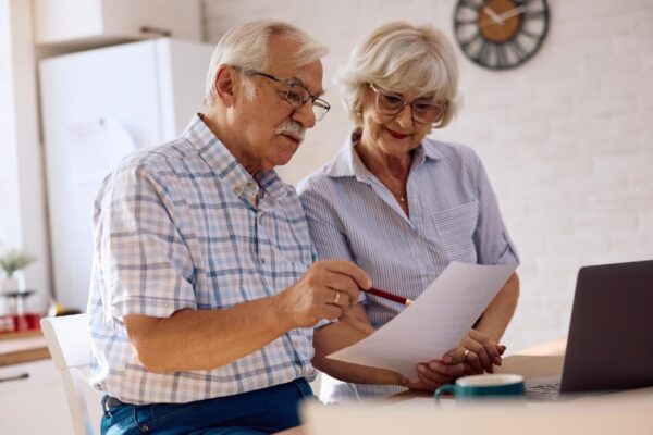 Senior couple analyzing home finances while using computer at home