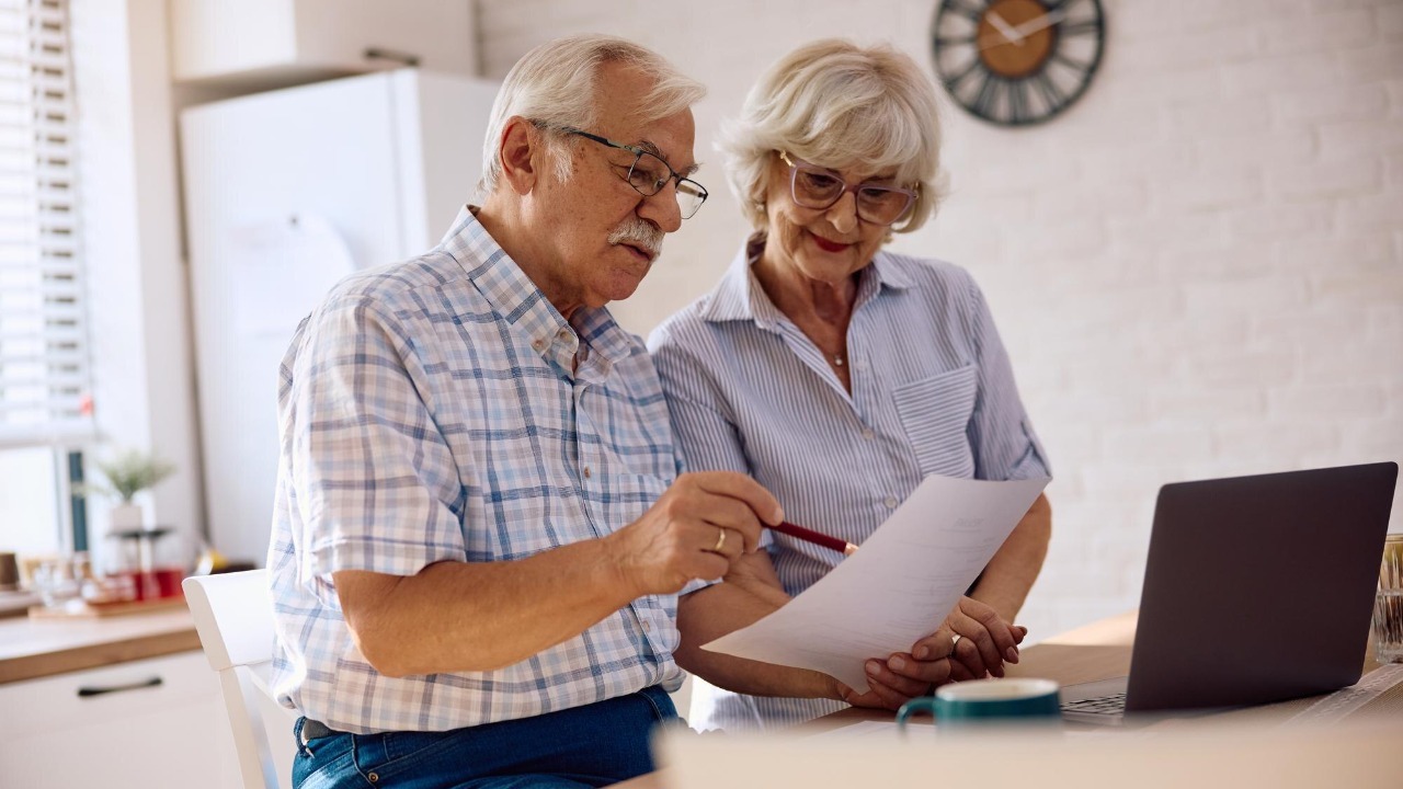 Senior couple analyzing home finances while using computer at home