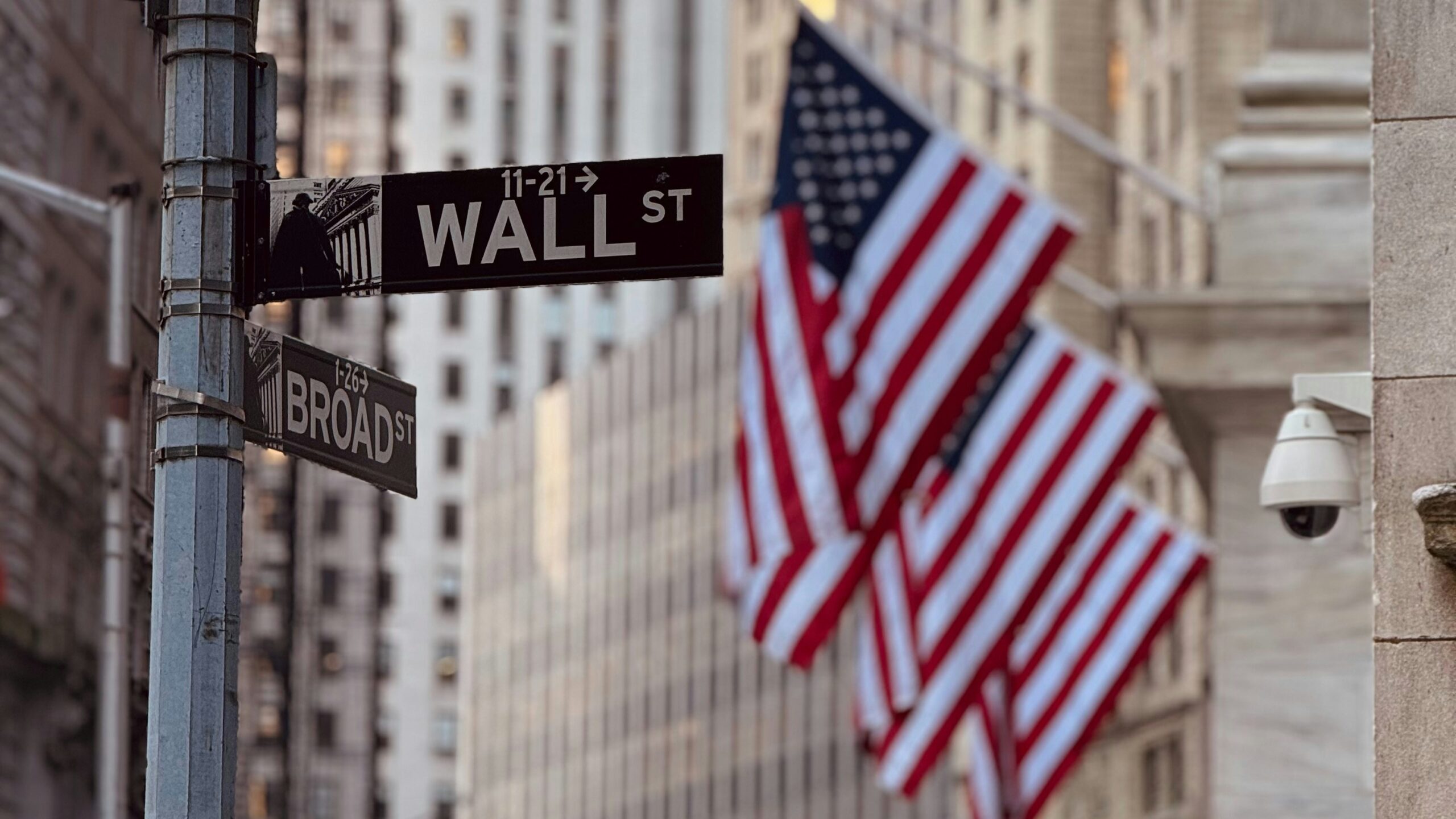 Wall street sign with american flags in the background.