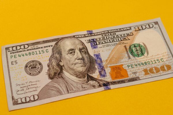 a hundred dollar bill laying on a yellow surface