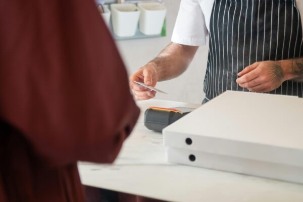 Chef receiving card payment for pizza order in a restaurant.
