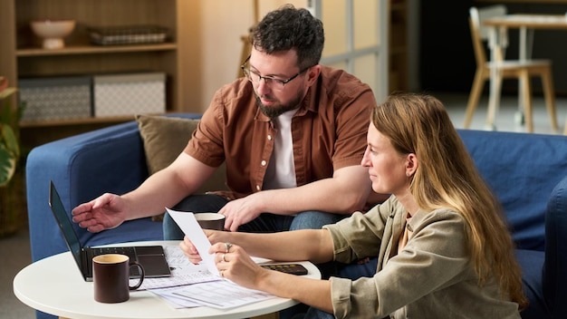 Caucasian young adult man and woman collaborating on tax preparation at home